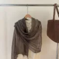 Detail view of the brown crinkled scarf with golden threads and fringe for women. - Coffee