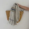 Detail shot of a lightweight linen scarf featuring stylish multi-color stripes and frayed edge design. - Khaki