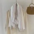 Detailed view of a retro striped crinkled scarf draped nicely for a cozy forest style look. - Off White