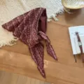 Vista dettagliata di un elegante fazzoletto triangolare floreale bordeaux con frange sul tavolo. - 115*35cm / Rosso