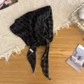 Detailed view of retro black and white checkered triangular scarf with scalloped white edges. - Black