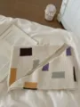 Close up detail of beige knit triangular shawl with colorful geometric block patterns. - Color Block Triangle Scarf / Color Block Triangle Scarf Beige