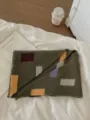Detailed shot of a stylish color-blocked knitted shawl on cozy bed linen with book. - Color Block Triangle Scarf / Color Block Triangle Scarf Green