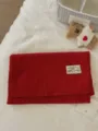 Red knit scarf detail close-up, soft woolen fabric texture with brand label and cute bear prop. - Bright Red