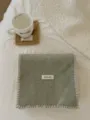 Primer plano de bufanda de punto de color sólido con puntada blanca y etiqueta. - Verde Frijol