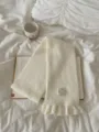 Cozy white knitted scarf for women, featuring a chic ruffle hem and stylish decorative label. - White