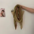 Vue détaillée d'une écharpe patchwork vintage usée, suspendue dans un panier en osier texturé. - Jaune Terre