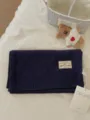 Close-up detail of a dark blue solid knitted wool scarf featuring a woven label and tag. - Navy Blue