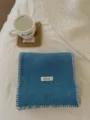 Primer plano detallado de bufanda de punto azul acogedora con costura blanca y etiqueta. - Azul