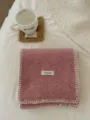 Vista detallada de una bufanda de punto de invierno rosa acogedora con borde blanco y etiqueta. - Rosa