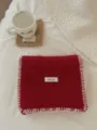 Detalle de bufanda de punto rojo acogedor con bordes de puntada de manta y etiqueta elegante. - Rojo
