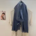 Gedetailleerd overzicht van de blauwe franjesjaal gedrapeerd op een shirt, licht materiaal. - 180x60cm / Blauw