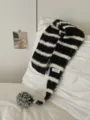 Detail shot of a black and white striped knitted scarf featuring a cozy pom-pom and product tag. - Contrast Striped Pom-Pom Black