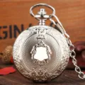 Detailed view of vintage silver pocket watch with intricate carved shield and metal chain. - Silver