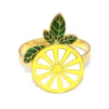 Gold metal lemon slice napkin ring detail, green leaf decor for elegant table setting. - Lemon