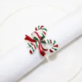 Close-up of Christmas candy cane napkin ring with red green enamel bow design on white napkin. - Candy Cane Style