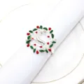 Detailed view of silver Christmas reindeer napkin ring featuring red and green festive decor elements. - Deer