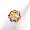 Close-up detail of gold Christmas elk napkin ring featuring red berries and green leaves. - 13