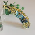 Detail view of gold alloy butterfly banana hair clip with blue rhinestones and enamel petals. - Blue