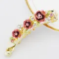 Gold-tone metal banana hair clip featuring colorful enamel flowers and sparkling rhinestones. - Pink