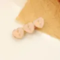 Barrette à cheveux dorée avec trois cœurs émaillés roses et de délicats motifs floraux. - Rose