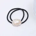 Chouchou élastique noir avec perle ovale et strass au centre, accessoire de coiffure élégant. - Style Perle Ovale