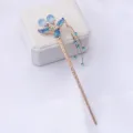 Gros plan détaillé d'un bâton de cheveux chinois doré vintage avec des strass bleus et pampilles. - Bleu