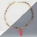 Gros plan sur le collier de perles colorées avec pendentif poisson émail rose, détails. - Rose rouge
