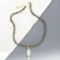 Gros plan sur un collier de perles en pierre naturelle avec pendentif poisson emaille blanc. - Blanc