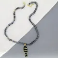 Détail gros plan du collier de perles bleues avec un joli pendentif poisson émaillé. - Noir