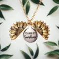 Detail shot of sunflower locket necklace, engraved pendant design with metallic texture. - Gold