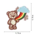 Close-up of cute cartoon teddy bear and rainbow cloud embroidered patch detail, fine craft. - Flying Bear