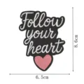 Nahaufnahme des schwarzen gestickten Aufnähers mit Follow your heart Text und rosafarbenem Herz. - FOLLOW YOUR HEART