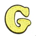Yellow letter G embroidered patch, close-up view of fabric clothing accessory and repair patch badge. - Letter G