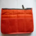 Detailed view of orange handbag organizer insert with multiple mesh pockets and secure zip top. - M / Orange