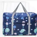 Bolsa de viaje plegable azul con estampado de globos, asas grises y bolsillo frontal con cremallera. - Globo Marino