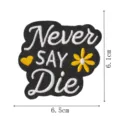 Nahaufnahme Detail des schwarzen bestickten Aufnähers mit weißer Schrift und gelber Blume. - Never say die
