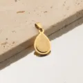 Gros plan du pendentif goutte d'or, montrant la texture givrée délicate et son anneau. - Larme / Or