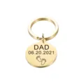Detailopname van gepolijste roestvrijstalen ronde sleutelhanger met gegraveerde papa en baby. - Goud