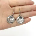 Detailed shot of silver round mermaid fish scale dangle earrings held in hand for women. - AB Color