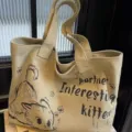 Detail view of beige canvas tote bag showing cute cat illustration and handle stitching. - Little Mouse Khaki