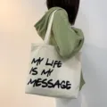 Casual canvas shoulder bag for women, large capacity daily tote with stylish letter print. - White
