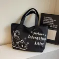 Black canvas tote bag detail view, featuring cute cat graphic and letter print, daily casual style. - Black