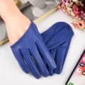 Detailed view of blue full-finger PU leather gloves displayed in a modern prop setup. - Blue