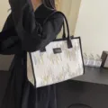 Detail view of the white canvas tote bag with embroidered tassel accents and black trim. - Off White
