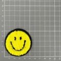Vue détaillée du patch brodé smiley chenille jaune sur fond quadrillé pour décoration. - Visage Souriant Classique (1C6-3)