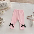 Toddler girls solid color leggings detail view, featuring cute black bows and soft elastic fabric. - 66cm / Bottoms / Pink