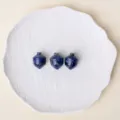 Natural blue crystal carved acorn mini stone ornaments displayed on a white ceramic plate. - Sodalite