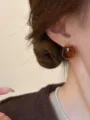 Close-up detail shot of vintage amber round stud earrings showing glossy texture and rich color. - A2877 A-Style