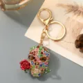 Detailed view of rhinestone skull keychain with red rose, gold tone metal bag pendant. - Colorful